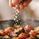 [dark] Detaljebillede: Close-up af en konkret ‘klog’ køkkendetalje (fx salt der drysses, olie i stråle, eller termometer i kød/grønt). Bruges i feature-sektioner og som visuelt bevis på teknik.